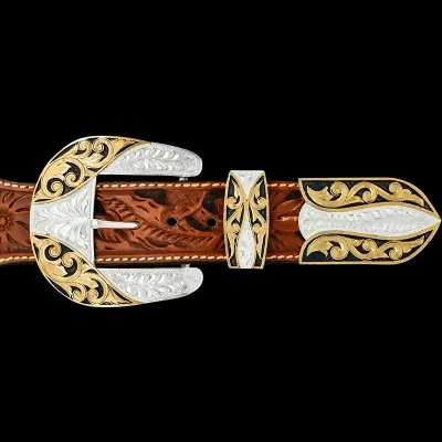 A custom western three piece belt buckle set featuring a silver plated base with golden bronze scrollwork and black enamel